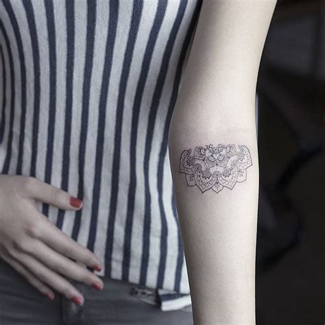 Fine line style half mandala tattoo on the forearm.