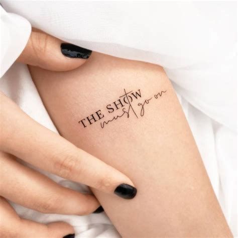 "The show must go on" lettering tattoo on the inner