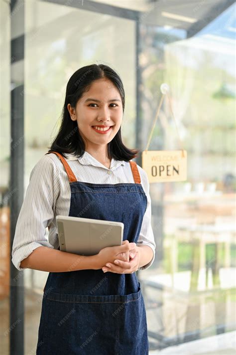 Premium Photo | Friendly young asian female waitress stands at the