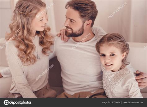 Happy young family with one child sitting embracing together at home ...