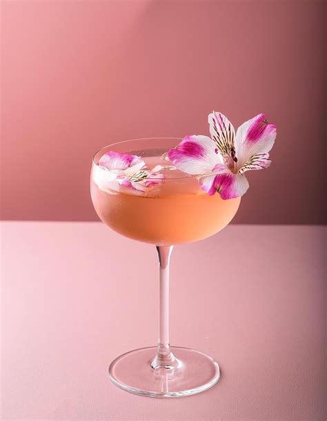 Cocktail with edible flower garnish, on pastel background 51444045