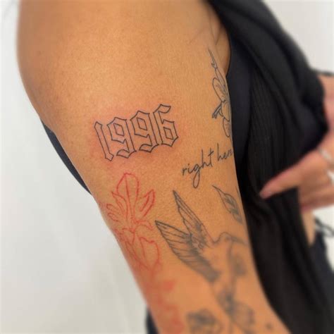 "1996" lettering tattoo located on the upper arm.